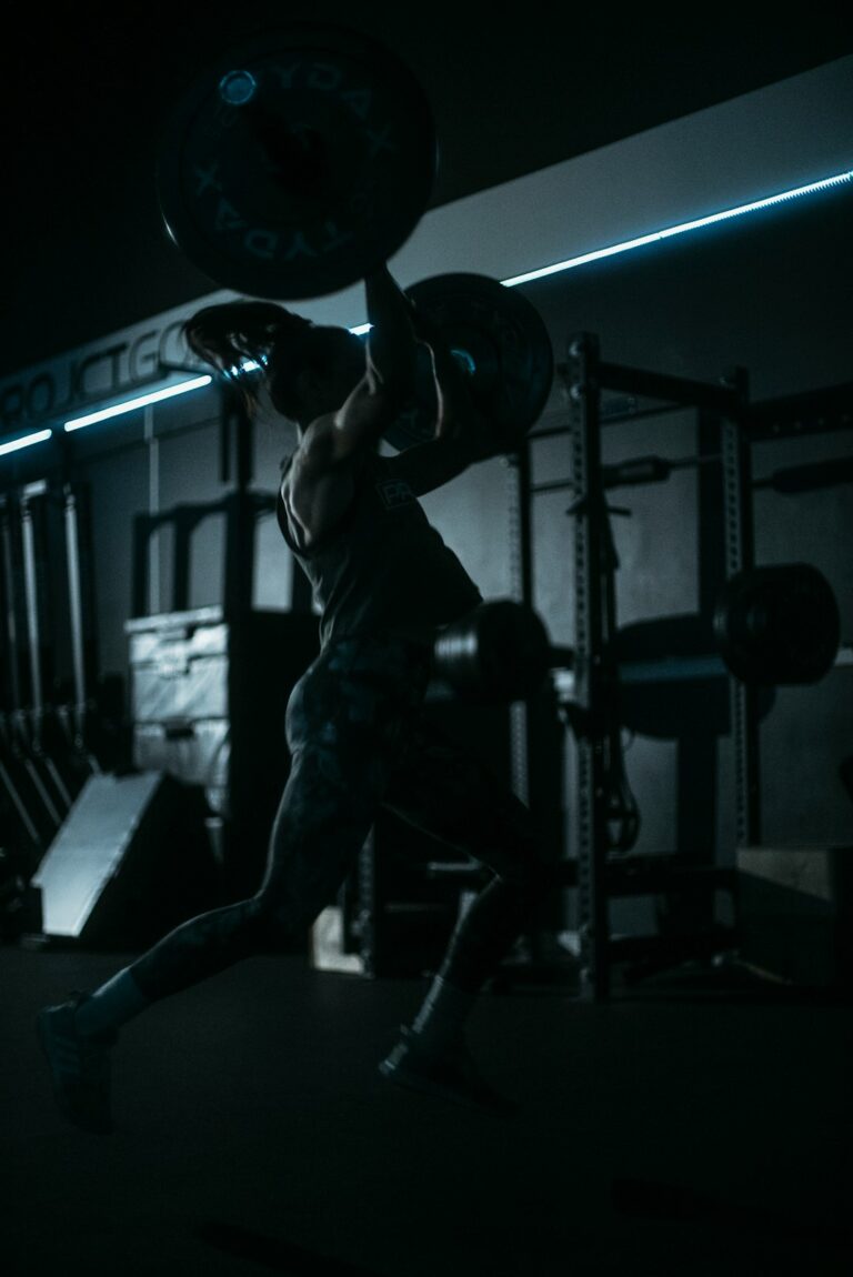 Man lifting barbell in a dark gym - strength training program
