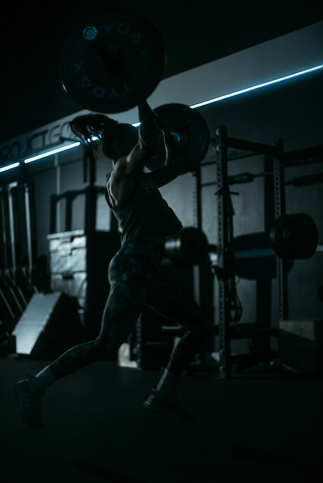 Man lifting barbell in a dark gym - strength training program